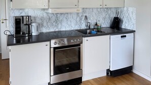 A kitchen with white cabinets, a stainless steel stove, a dishwasher, and a marble backsplash. - GG Village (Askim)