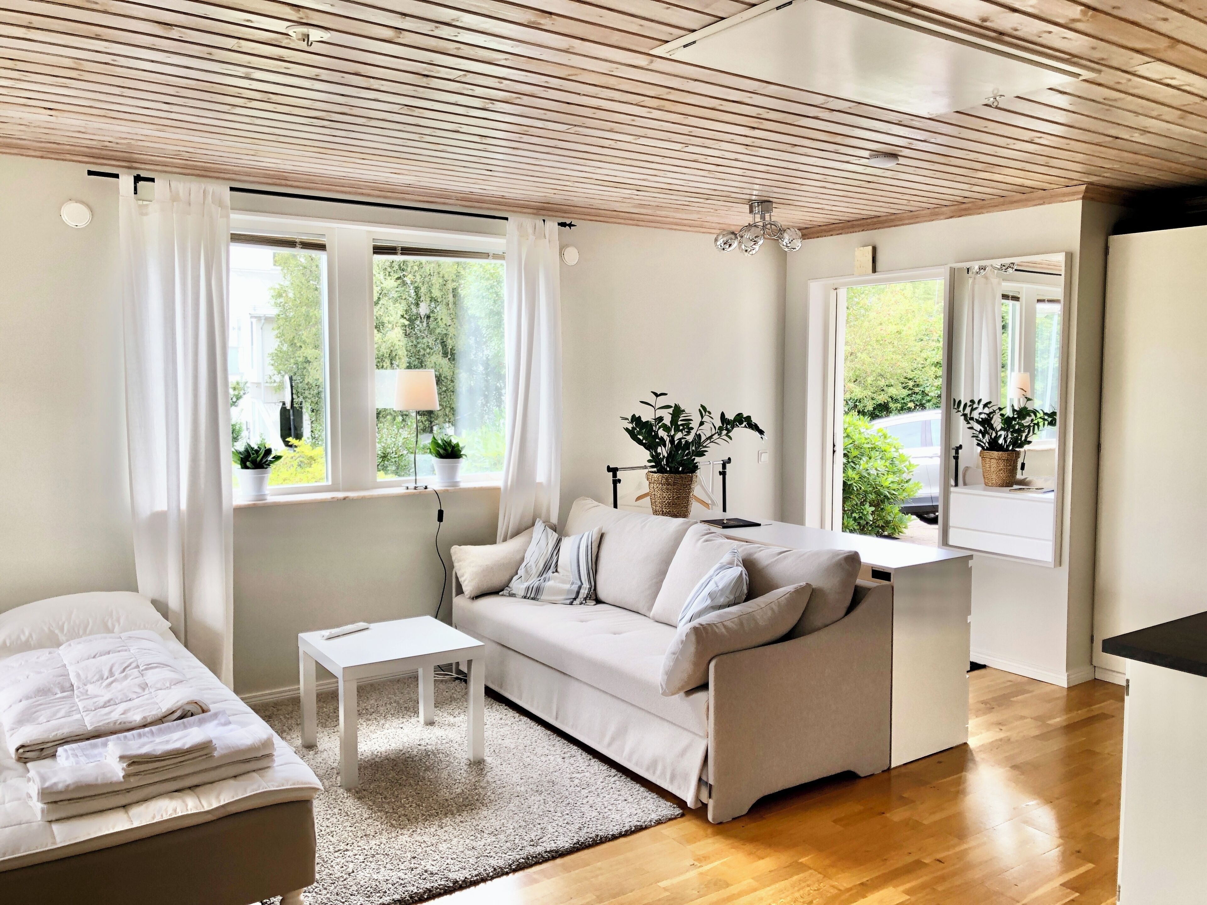 A modern living room with a sofa, a small table, and a window with curtains.
