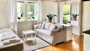 A modern living room with a sofa, a small table, and a window with curtains. - GG Village (Askim)