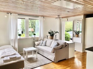 A modern living room with a sofa, a small table, and a window with curtains.