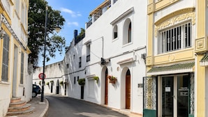 A street with white buildings, a no parking sign, and a shop with a green door. - Kortobi Central Stay – 2-Bedroom Apartment Near the Old Medina (Tanger)