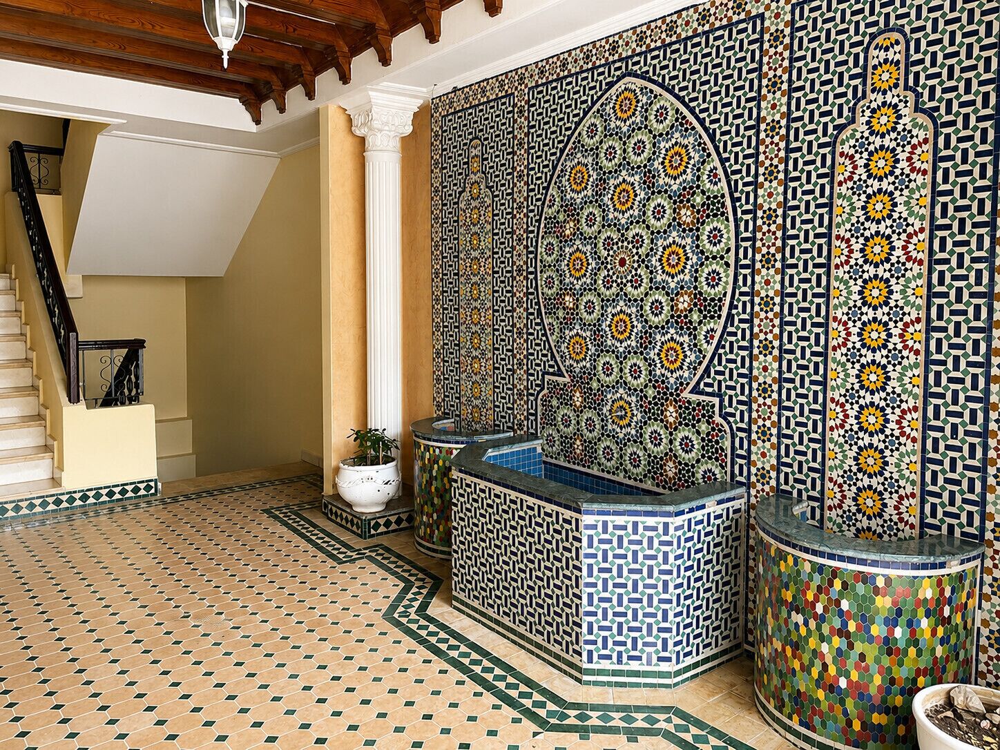 A room with a tiled floor, a staircase, and a decorative wall with intricate patterns.