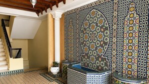 A room with a tiled floor, a staircase, and a decorative wall with intricate patterns. - Kortobi Central Stay – 2-Bedroom Apartment Near the Old Medina (Tanger)