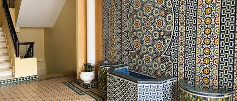 A room with a tiled floor, a staircase, and a decorative wall with intricate patterns.