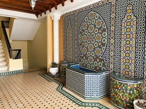 Ein Zimmer mit Fliesenboden, einer Treppe und einer Wand mit aufwendigen Verzierungen.