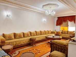 A traditional living room with a sofa set, a coffee table, and a chandelier. - Kortobi Central Stay – 2-Bedroom Apartment Near the Old Medina (Tanger)