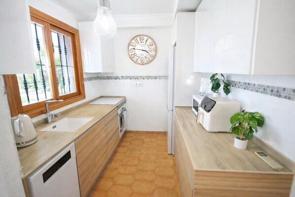A modern kitchen with a wooden countertop, a sink, a stove, a refrigerator, and a clock on the wall. - Casa Cabo Roig, a 2-minute walk from Cabo Roig Beach (VC)