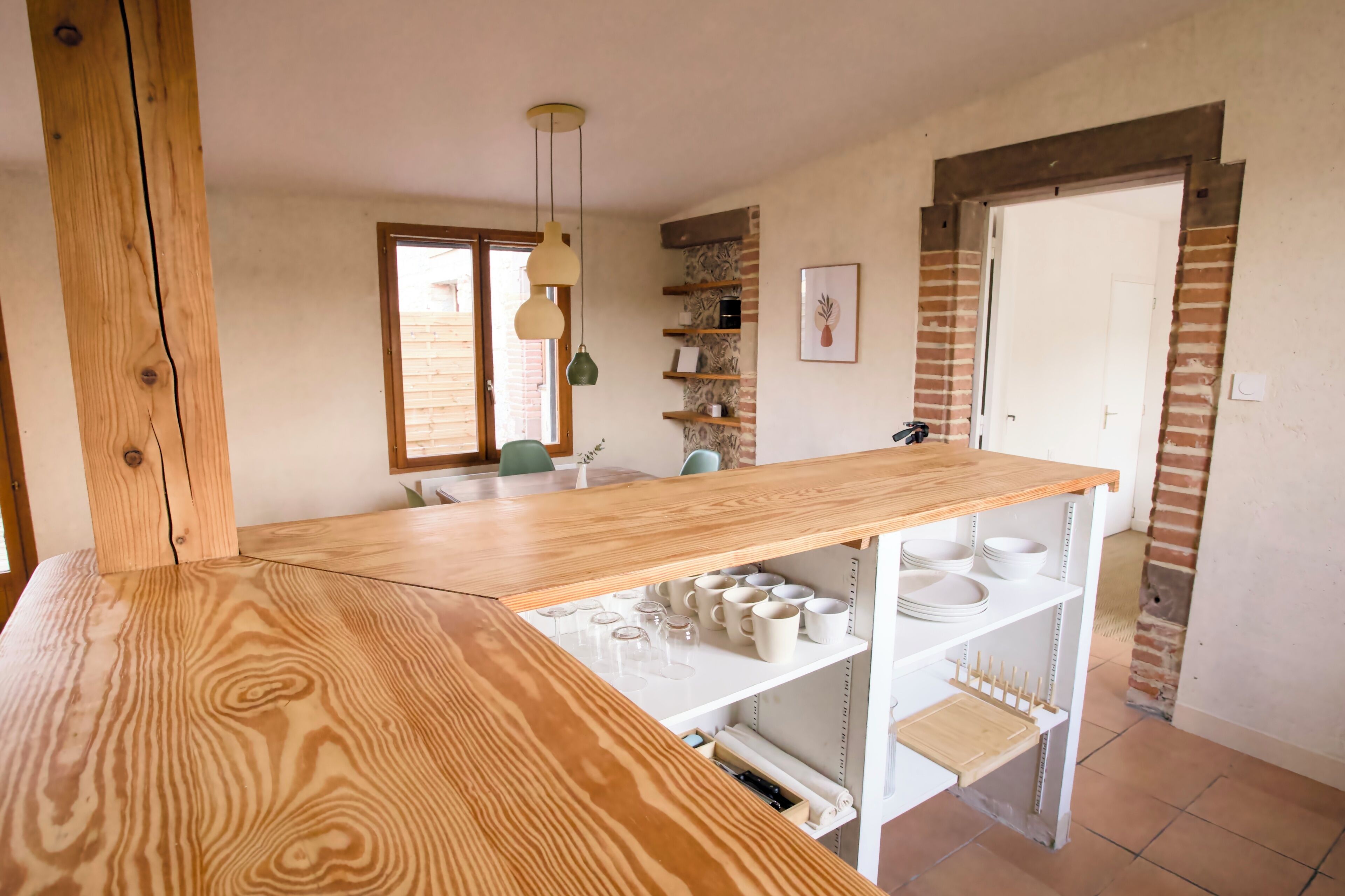 A kitchen with a wooden countertop, white cabinets, and a hanging light fixture.