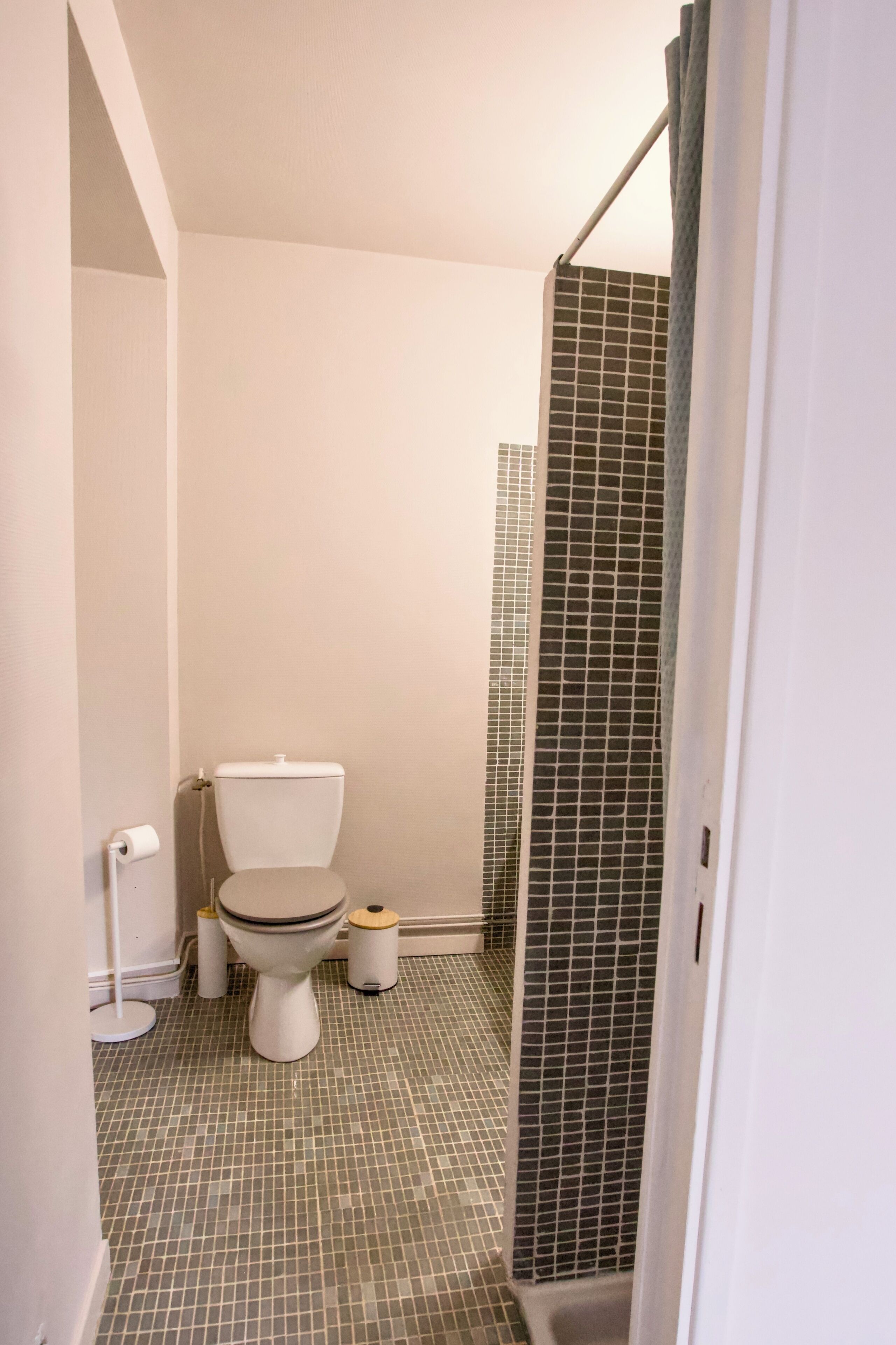 Een badkamer met toilet, bidet en een douchegedeelte met betegelde wanden.