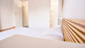 A hotel room with a bed, a wooden headboard, a wardrobe, and a door leading to another room. - Quiet cottage with a terrace, 3 minutes from Albi (Castelnau-de-Lévis)