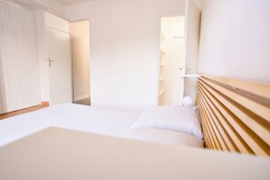 A hotel room with a bed, a wooden headboard, a wardrobe, and a door leading to another room. - Quiet cottage with a terrace, 3 minutes from Albi (Castelnau-de-Lévis)
