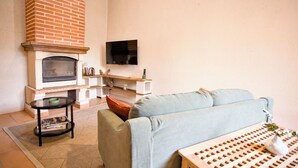 A living room with a fireplace, a flat-screen TV, a sofa, and a coffee table. - Quiet cottage with a terrace, 3 minutes from Albi (Castelnau-de-Lévis)