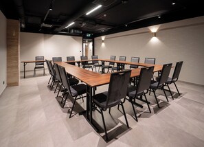 A conference room with a long table and chairs, a wooden accent wall, and a ceiling with exposed pipes and lighting. - Tower Hotel Wrocław (Wrocław)