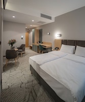 Habitación de hotel con una cama grande, un escritorio, una silla y una mesita con un jarrón de flores.