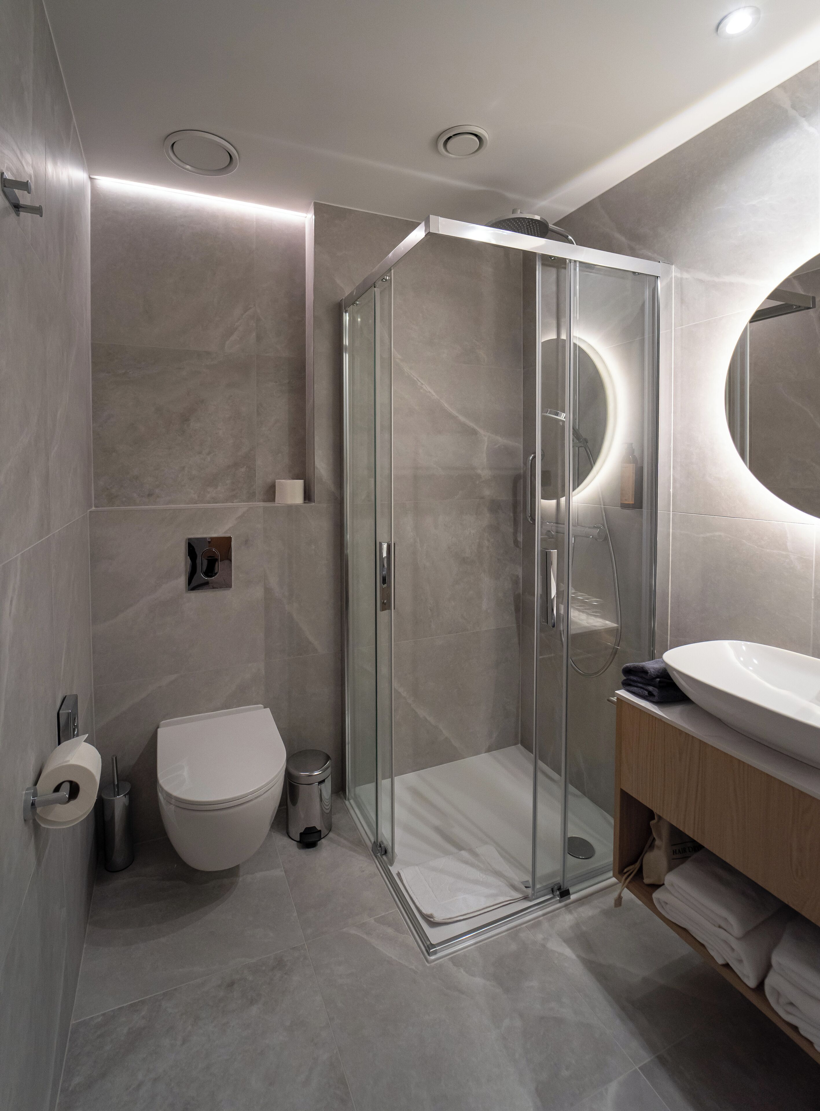 Une salle de bain moderne avec une douche à parois de verre, des toilettes et un lavabo avec un miroir.