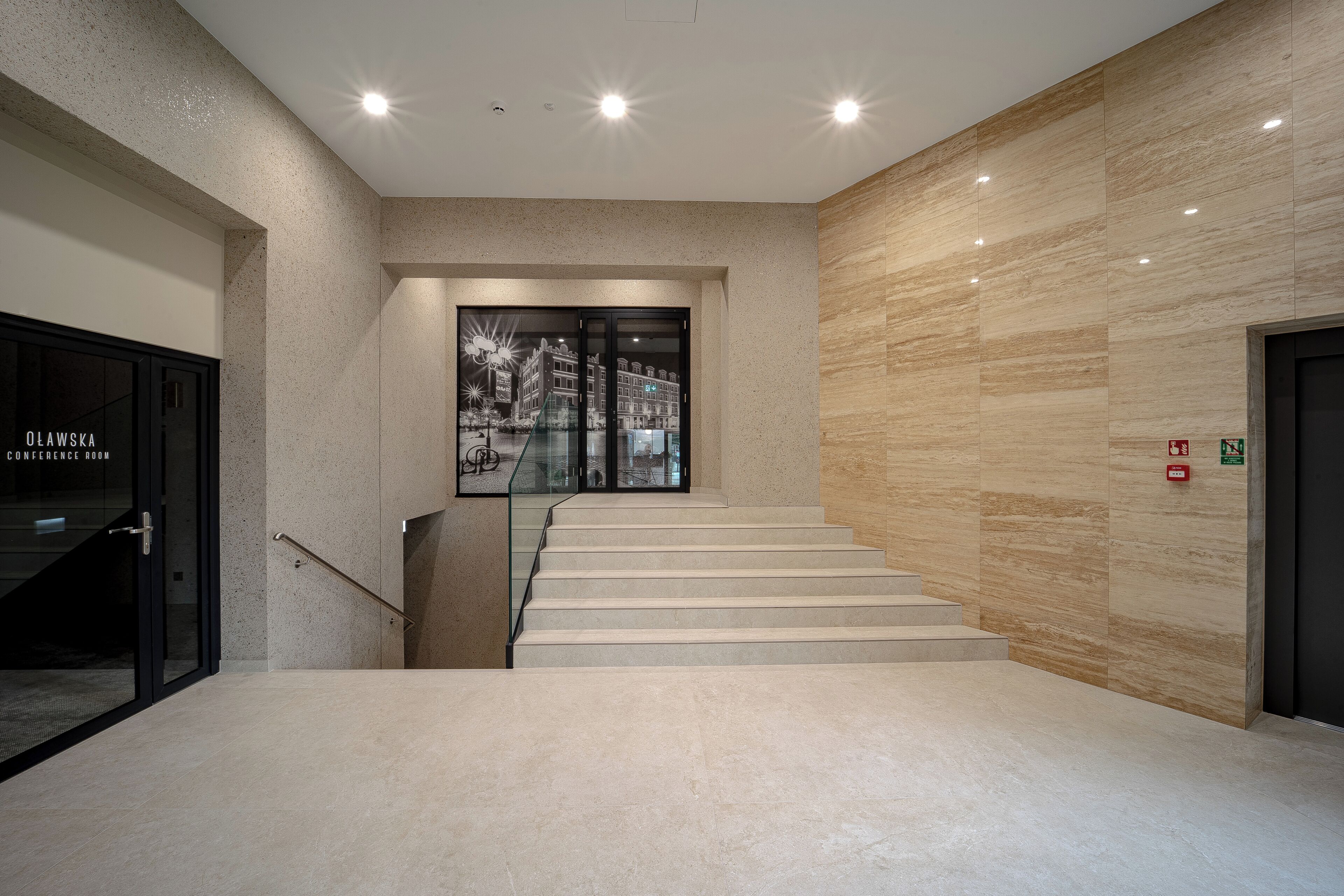 A modern interior with a staircase, a conference room, and a wall with emergency exit signs.