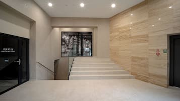 A modern interior with a staircase, a conference room, and a wall with emergency exit signs.