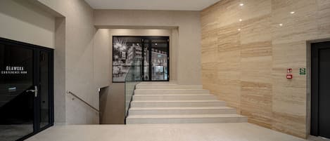 Un intérieur moderne comprenant un escalier, une salle de conférence et un mur avec des panneaux indiquant les sorties de secours.