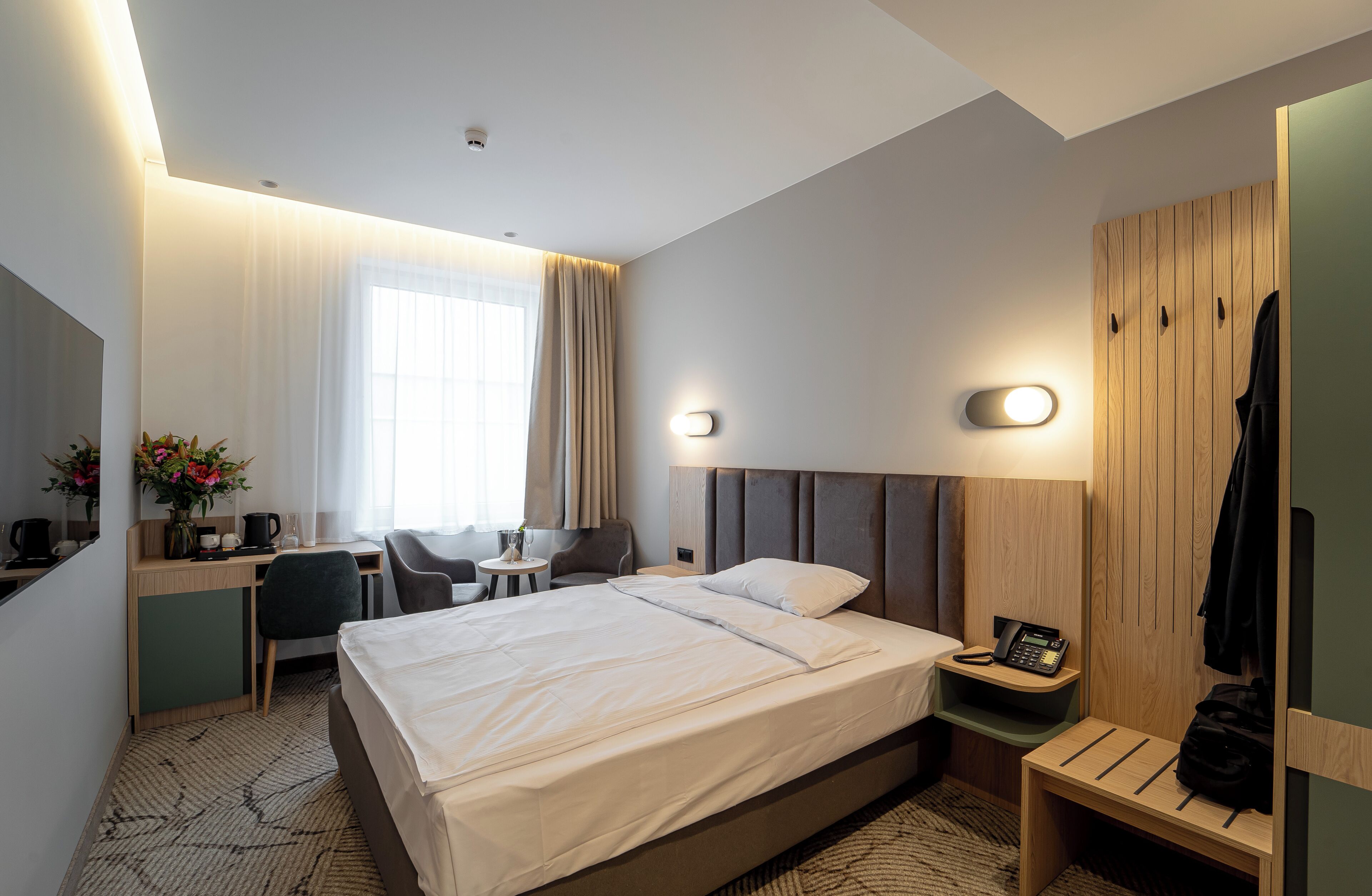 Ein Hotelzimmer mit Bett, Nachttisch, Schreibtisch, Stuhl und Kleiderschrank.