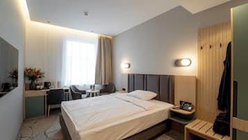 Ein Hotelzimmer mit Bett, Nachttisch, Schreibtisch, Stuhl und Kleiderschrank.
