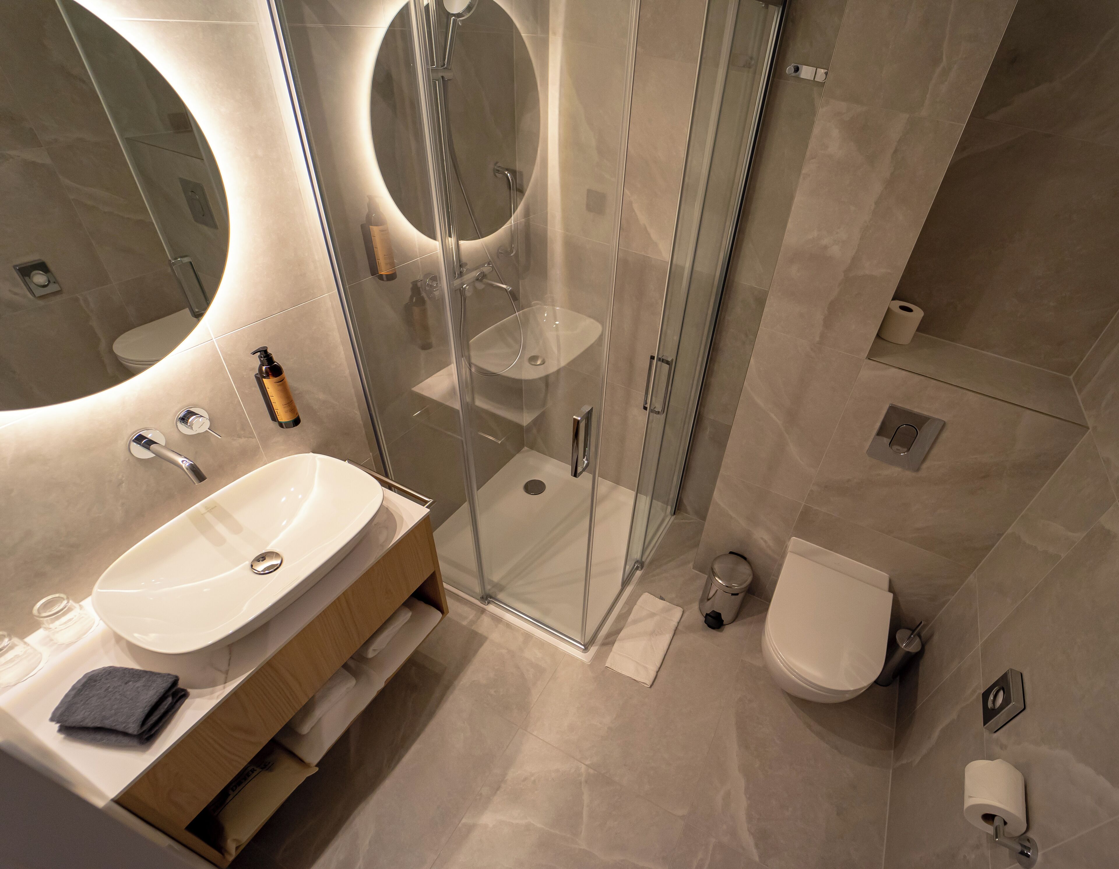 Un baño moderno con ducha de vidrio, lavamanos blanco y inodoro.