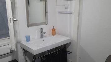 Un bagno con lavandino bianco, specchio e water.