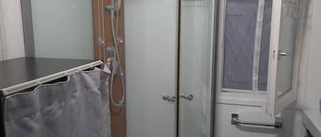 A shower enclosure with a glass door, a showerhead, and a towel rack.