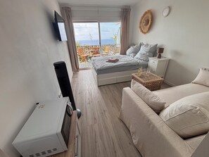 A bedroom with a bed, a sofa, a TV, and a heater. - Luxury Apartment by the Sea, Cala Llevado (Tossa de Mar)