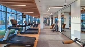 Une salle de sport moderne équipée de tapis de course, d’appareils de musculation et de bancs d’exercices.