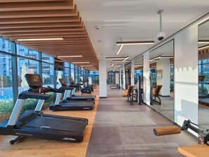A modern gym with treadmills, weight machines, and exercise chairs. - StayShort - Chic 1-Bedroom for 4 in Prime Dubai Hills Location! (Dubai Hills)