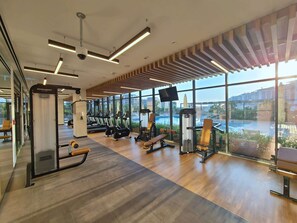 Una palestra moderna con attrezzature per esercizi, ampie finestre e vista sulla città.