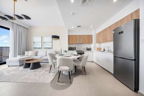 Una cucina moderna con frigorifero in acciaio inox, mobili in legno e un'area pranzo con un tavolo rotondo e sedie.