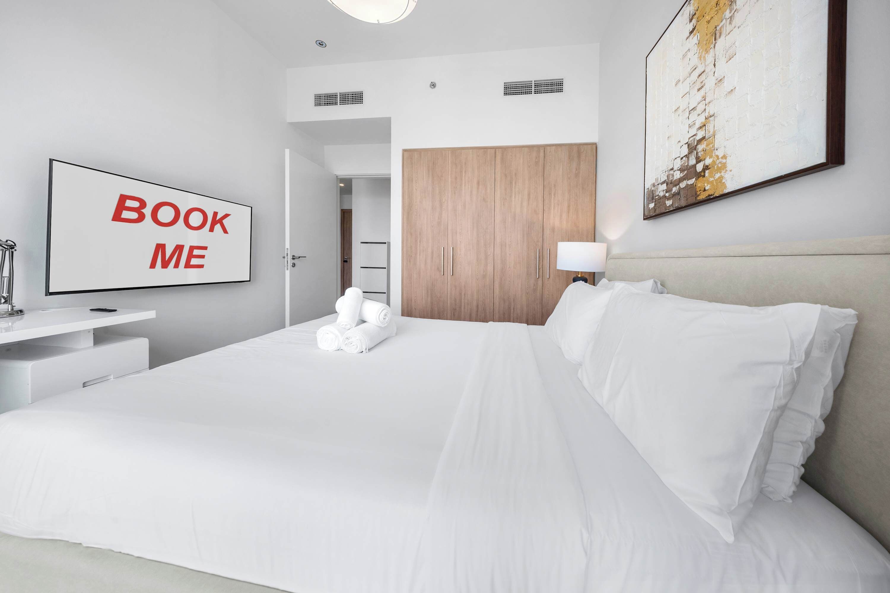 A hotel room with a bed, a desk, a TV, and a wardrobe.