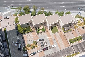 A modern building with a parking area and a road with directional arrows. - StayShort - Chic 1-Bedroom for 4 in Prime Dubai Hills Location! (Dubai Hills)
