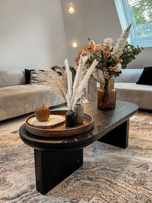 Un salon moderne avec une table basse ronde, un canapé et une fenêtre laissant entrer la lumière naturelle.