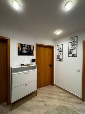 Ein Flur mit einer Holztür, einem weißen Schrank mit Schubladen und zwei an der Wand befestigten Bilderrahmen.