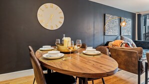 Ein Essbereich mit einem runden Holztisch, Stühlen und einer an der Wand befestigten Uhr.