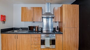 Eine moderne Küche mit Holzschränken, Edelstahlgeräten und einem eingebauten Backofen.