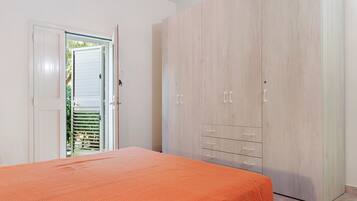 Een slaapkamer met een bed, een kledingkast en een deur naar een buitenruimte.