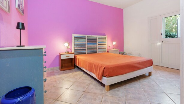 Una camera da letto con un letto, un comodino, una cassettiera e una finestra.