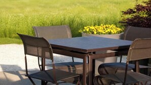 An outdoor patio with a table and chairs, surrounded by a grassy field and a flower pot. - La Terrasse Étoilée: Vacation rental attached to the owners' home, 1 bedroom, 4 (Saint-Médard-d'Excideuil)