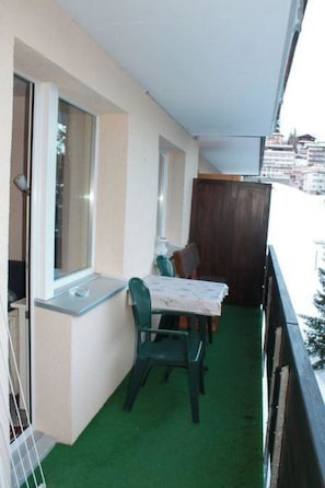 A balcony with a table and chairs, a window, and a view of buildings. - Haus Seewaldweg 309 Appartement/Fewo,  , 3-Bettwohnung 3-Bettwohnung by Interhome (Arosa)