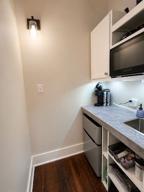 A compact kitchen with a microwave, a coffee machine, and a sink.