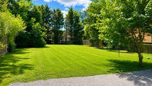 Une pelouse bien entretenue, avec un chemin de gravier menant à une clôture en bois.