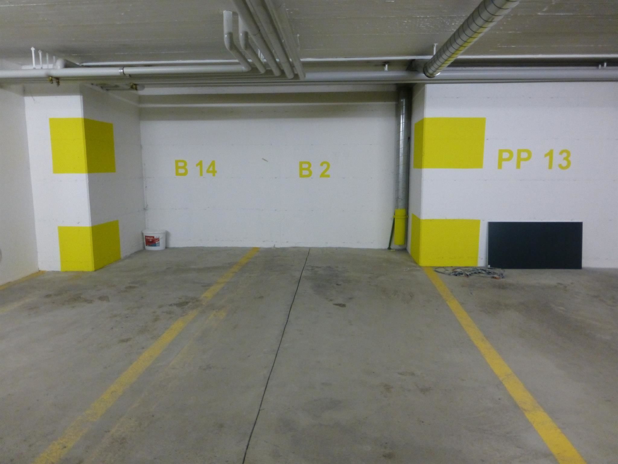 Um estacionamento com vagas demarcadas, B14, B2 e PP 13.