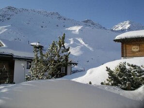 A snow-covered mountain landscape with a wooden cabin and a small building with a sloped roof.