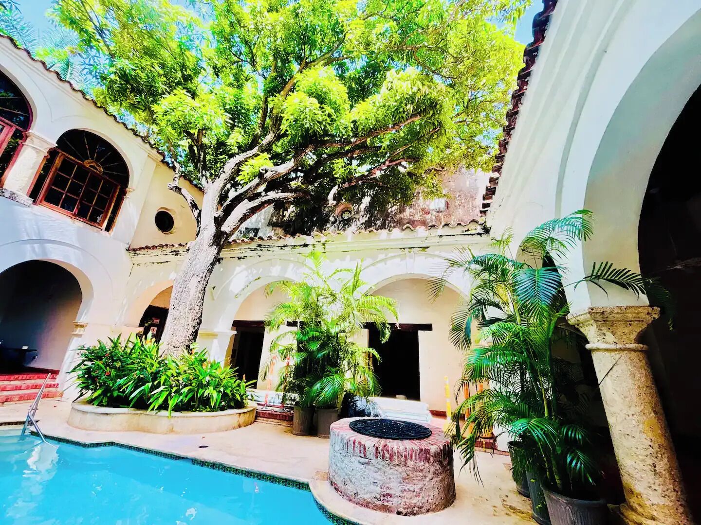 Un patio con piscina, rodeado de arcos y árboles.