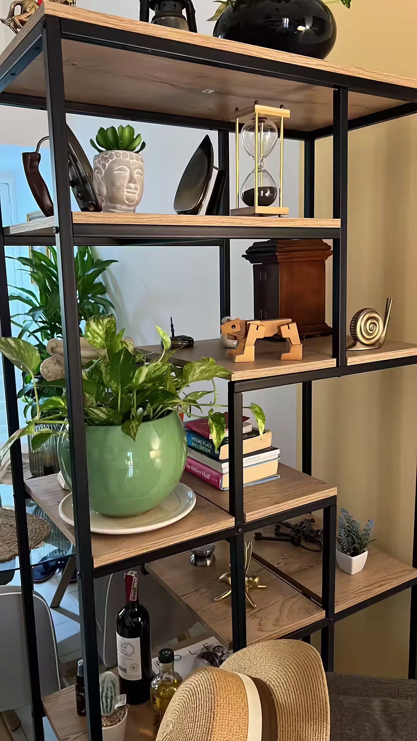 Een meerlaagse houten plankenwand met decoratieve objecten en planten.