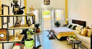 A well-lit room with a bed, a sofa, a coffee table, and a bookshelf. - Cozy Studio Apt. in charming Cartagena with AC (Cartagena)
