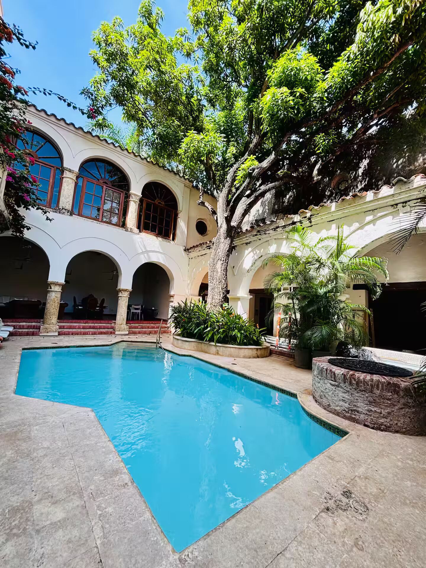 A courtyard with a swimming pool, arched walkways, and lush greenery.